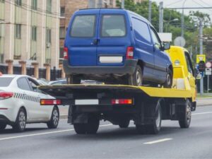 Furgone blu sopra un camioncino giallo per il trasporto veicoli