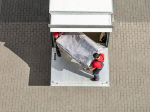 due operai trasportano un divano imballato nel furgone
