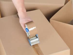 traslocatore sigilla con nastro adesivo un pacco per imballaggio trasloco