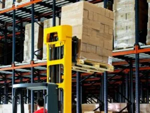 Carrello elevatore durante il sollevamento di diversi scatoloni in un deposito
