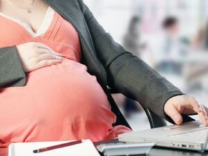 Donna in stato di gravidanza con computer e quaderno per organizzare il trasloco