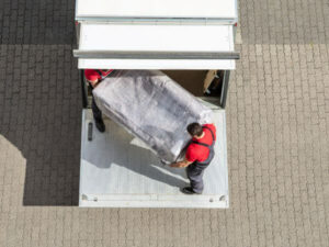 Operai trasportano nel mezzo di trasporto un divano imballato per trasloco