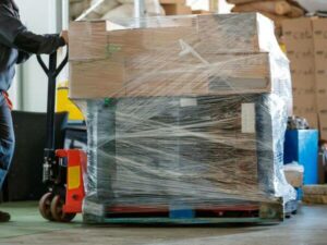 Imballaggio di scatoloni su un bancale trasportato su mezzo di trasporto con transpallet