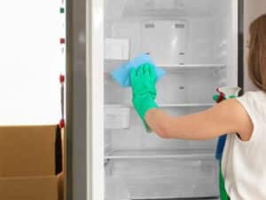 Donna pulisce interno del frigorifero per prepararlo al trasloco