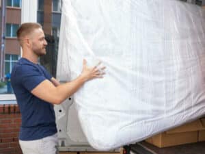 operaio trasporta materasso imballato nel furgone per il trasporto letto