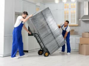 traslocatori trasportano un frigorifero imballato con un carrello