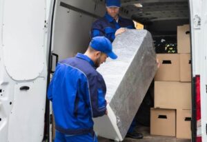 trasportatori durante il carico di un frigorifero imballato in un furgone